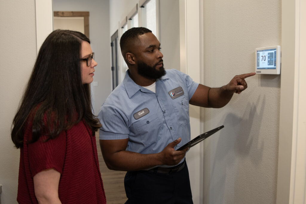Paschal technician reviewing a thermostat with a homeowner