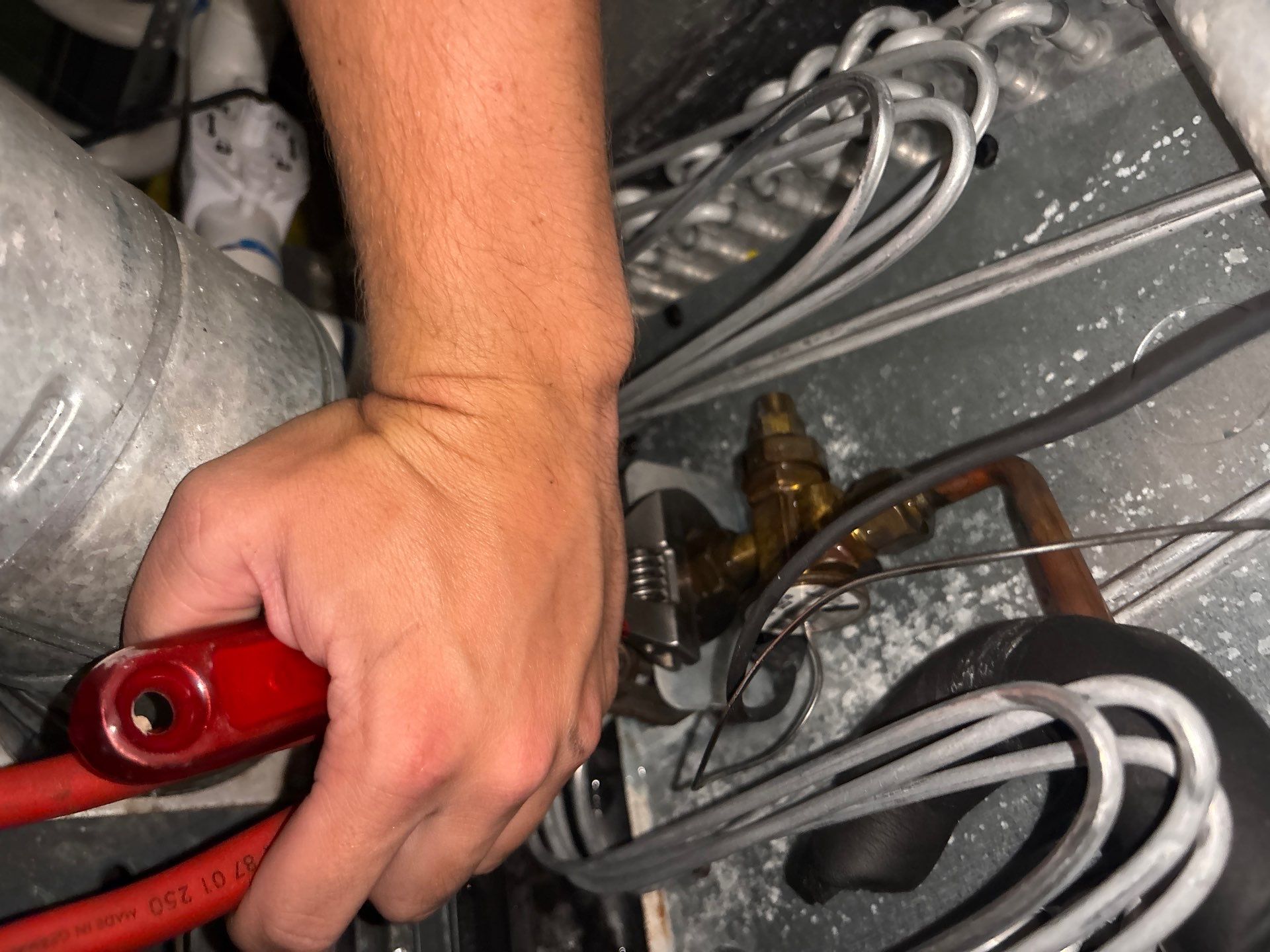 HVAC technician checking refrigerant lines and service valve on a Goodman AC in Springdale, AR