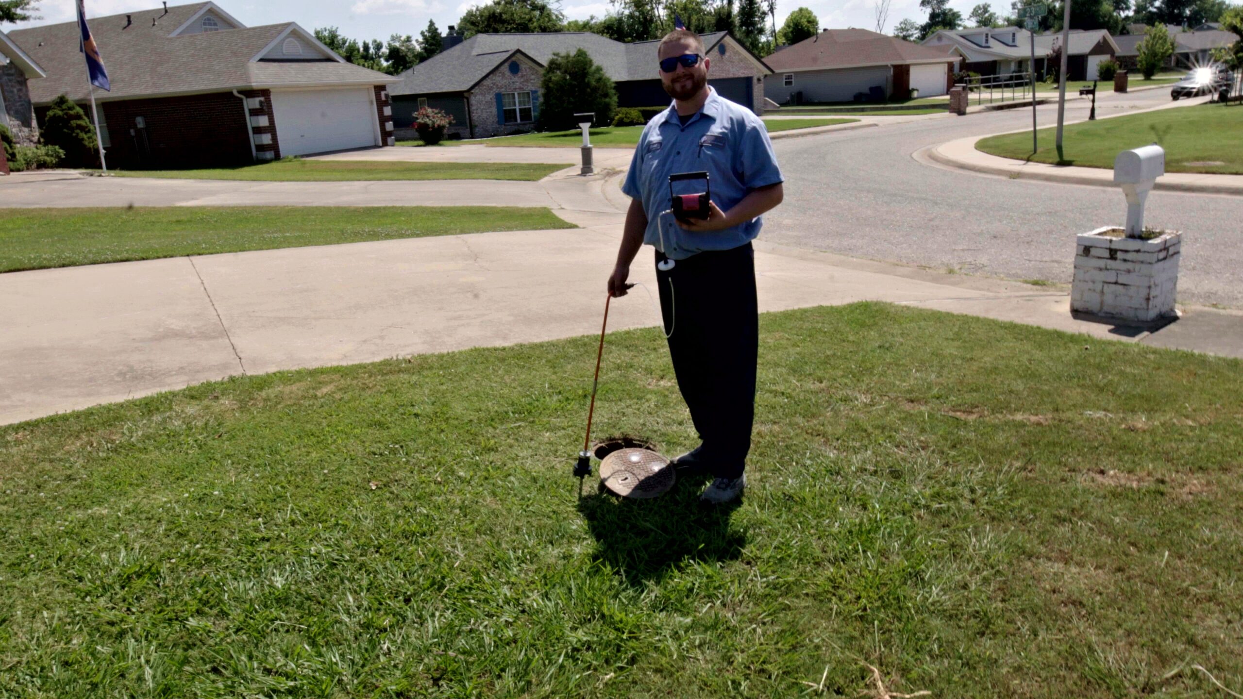 Smiling Paschal plumber next to a water meter after completing a leak detection service in Springdale