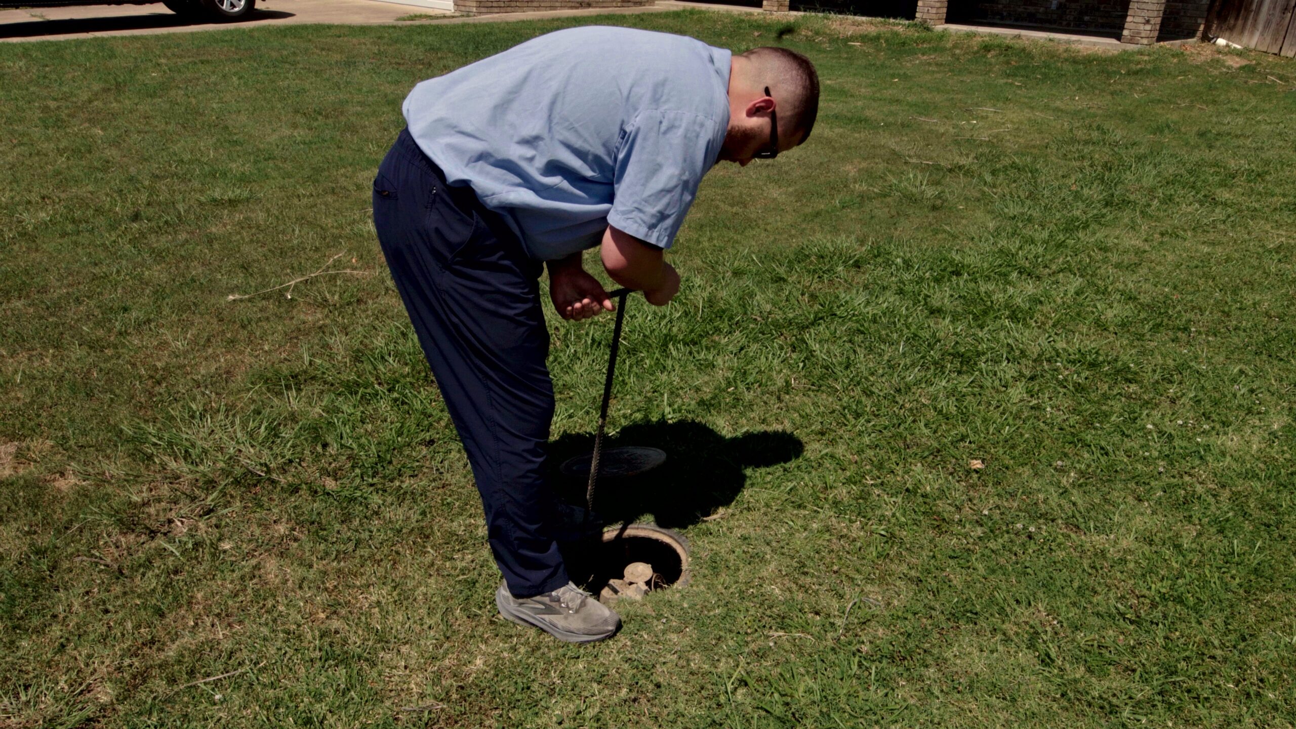 Paschal technician using a water meter key to isolate the water supply at the meter during leak detection in Springdale